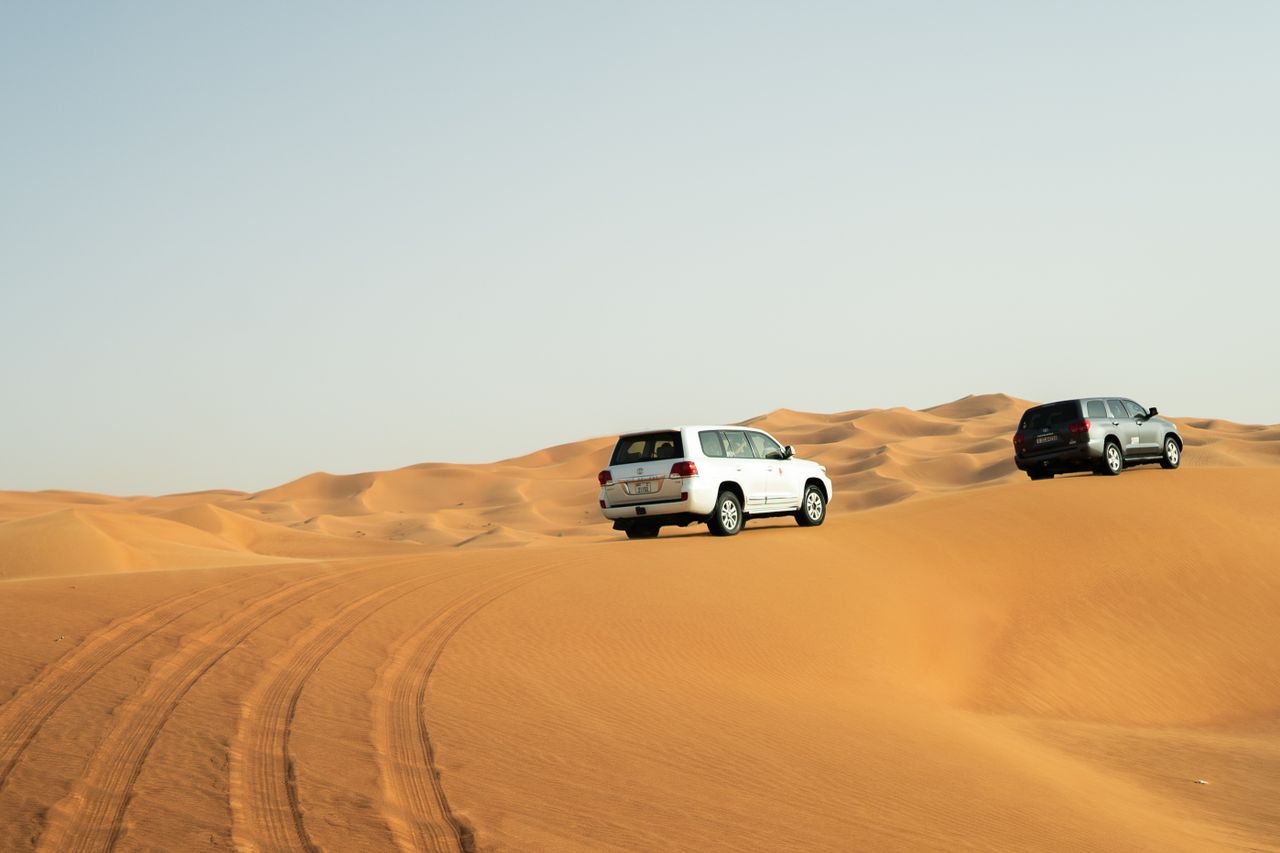 Two SUVs navigate the stunning sand dunes of Dubai, capturing adventure in the Arabian desert.