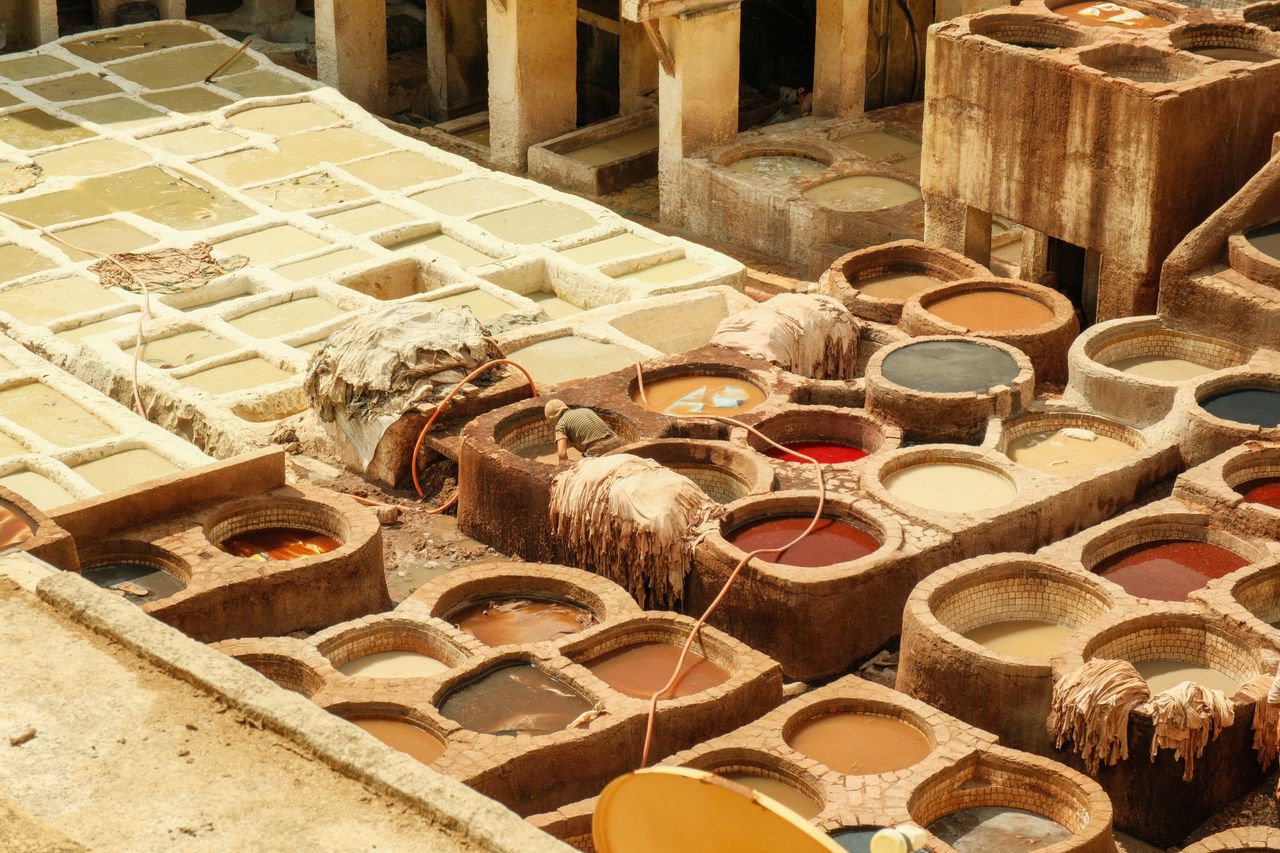 Vibrant view of a traditional tannery in Fes, Morocco, showcasing colorful dye vats and hides tanning in the sunlight.