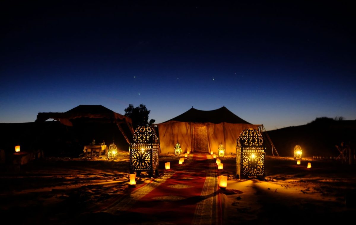 Lantern-lit tents at a desert camp at dusk, on a Fes desert tour