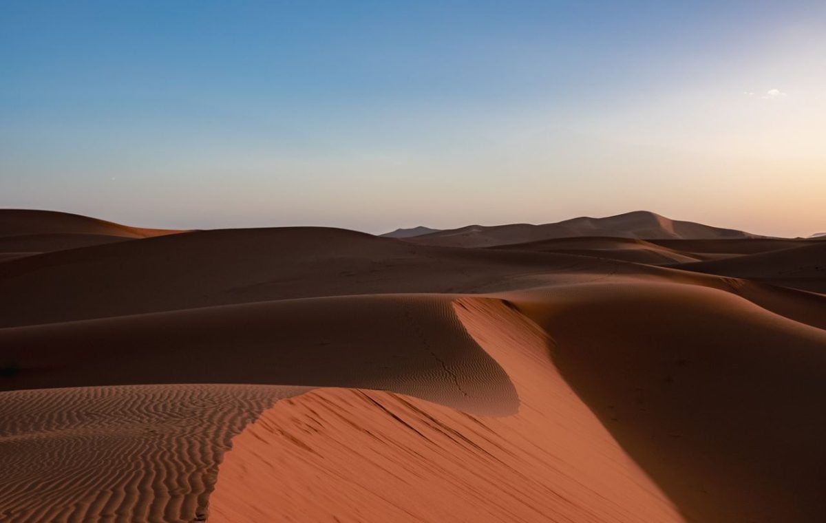 Sand dunes under a sunset sky